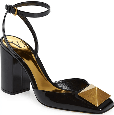 black patent pump with closed toe but open heel and an ankle strap; there is a single gold pyramid-like stud on top of toe area