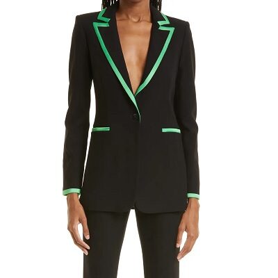 A woman wearing a black blazer with green piping, single-button closure.