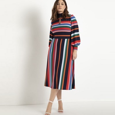 A woman wearing a multicolored striped dress with white sandals