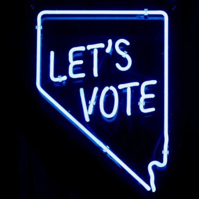neon sign reads "LET'S VOTE"
