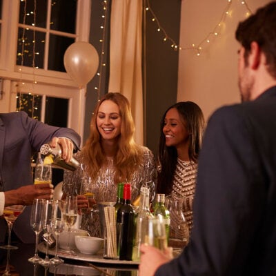 group of people toast drinks at their work holiday party at someone's house