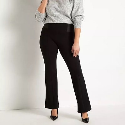 A woman wearing black pants, a gray sweater, and black heels