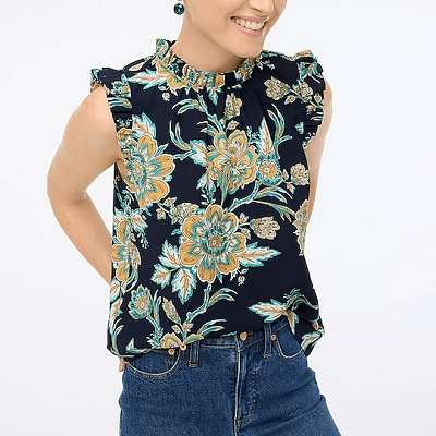 A woman wearing a black floral sleeveless top and blue jeans