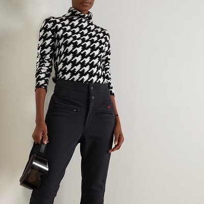 A woman wearing a black-and-white houndstooth sweater and black pants 