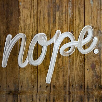 "nope" is written in cursive on a wood floor, possibly in soap