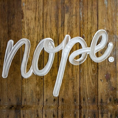 "nope" is written in cursive on a wood floor, possibly in soap