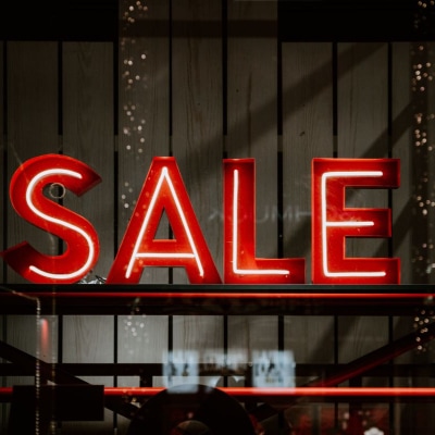 red neon letters spell SALE in a store window