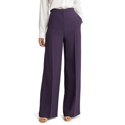 A woman wearing purple tailored pants and a white top