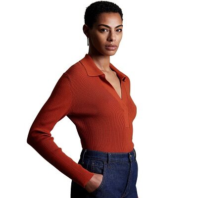 A woman wearing an orange collared sweater with dark blue jeans