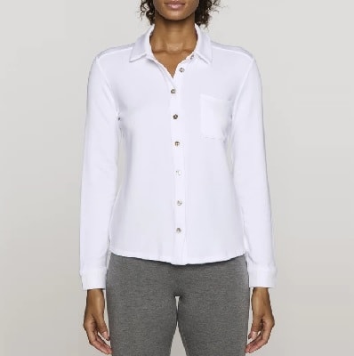 En kvinna klädd i en vit skjorta med knapp framtill och grå stickade byxor