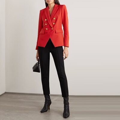 A woman wearing a red double-breasted blazer and black pants with black boots and a black bag