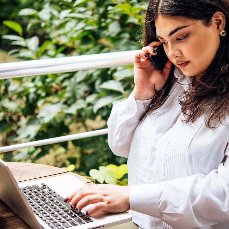 beautiful plus-size woman works from home with a laptop and cellphone