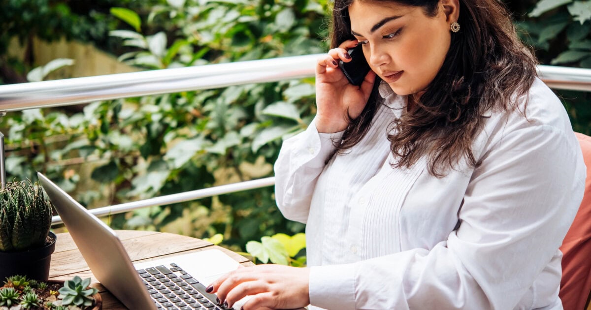 beautiful plus-size woman works from home with a laptop and cellphone