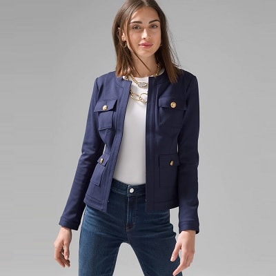 A woman wearing a navy  jacket, white top, and blue jeans