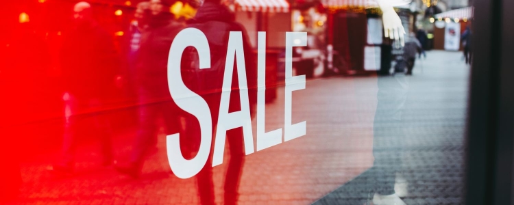 a store sign in window that reads SALE; window is reflecting the city street and photographer