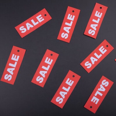 a number of red tags that say "SALE," laid on a table