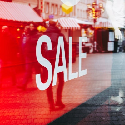 a store sign in window that reads SALE; window is reflecting the city street and photographer