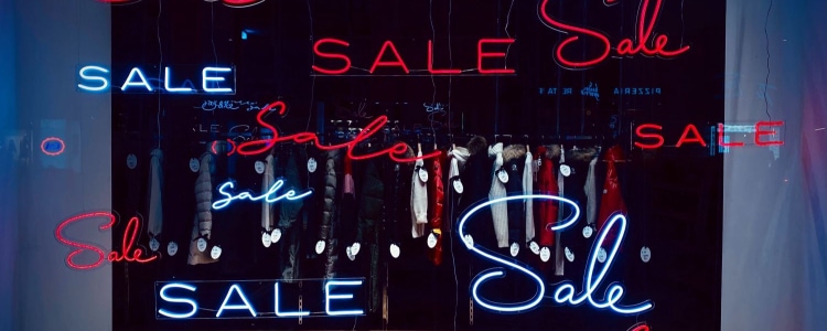 neon signs in a store window read SALE in a variety of fonts