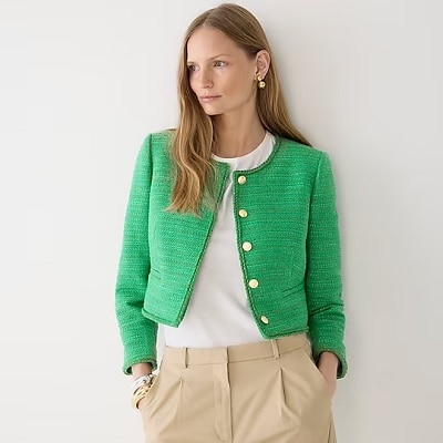 A woman wearing a white top, green tweed jacket and nude tailored pants