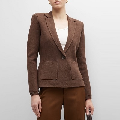 A woman wearing a brown knit blazer, ivory top, and brown pants