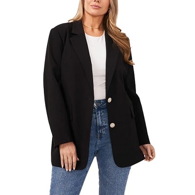A woman wearing a black blazer, white top, and blue jeans