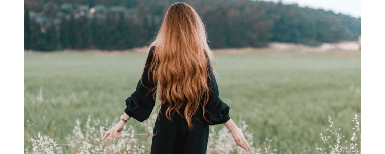 woman walks in a field; she has very very very long hair (to her bum)