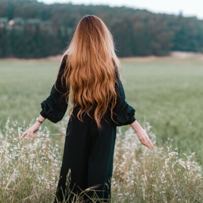 woman walks in a field; she has very very very long hair (to her bum)