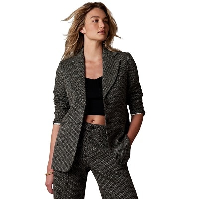 A woman wearing a black-and-white tweed blazer and pants, with a black crop top