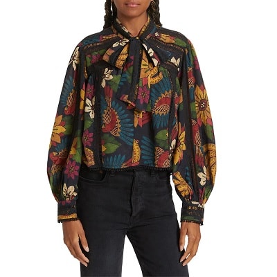 A woman wearing a multicolored print blouse and black jeans