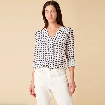 A woman wearing a white blouse with a navy geometric print and white pants