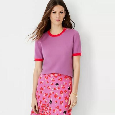 A woman wearing purple and red short-sleeved sweater with a coordinating floral-print skirt