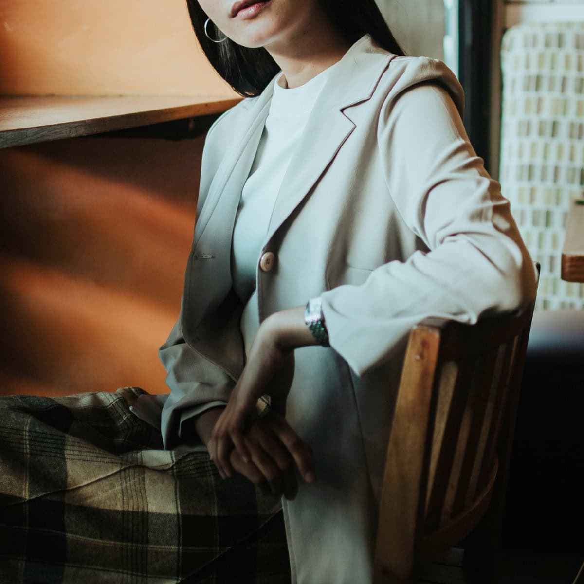 seated woman wears beige blazer and plaid skirt