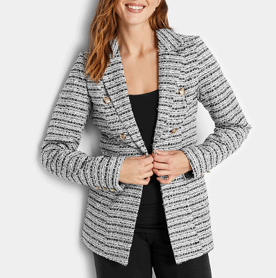 woman wears black and white boucle knit blazer with gold button detailing; she is wearing a black top and black pants under  it