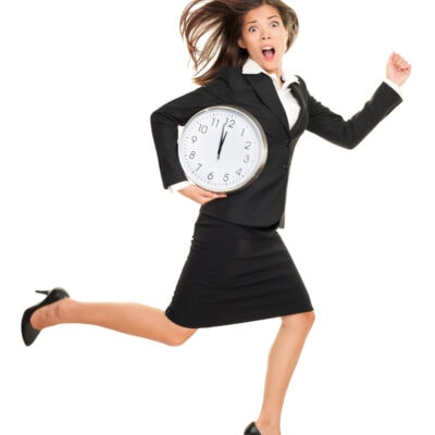 woman in skirt suit running in heels; she holds a large clock and looks alarmed