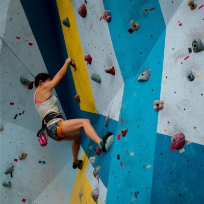 woman at an indoor rock climbing gym; she's having a weekly adventure!