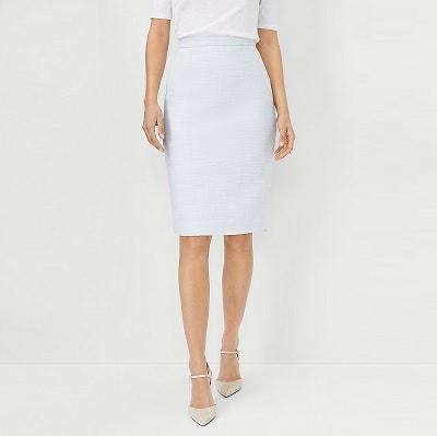 A woman wearing a white top, light blue pencil skirt, and nude heels