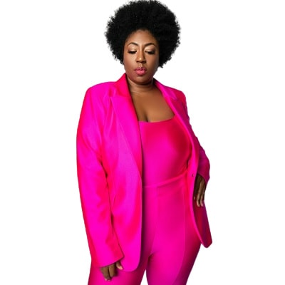 A woman wearing a bright pink suit, matching top, and beige heels