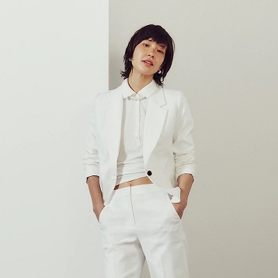 A woman wearing a white top and a white suit