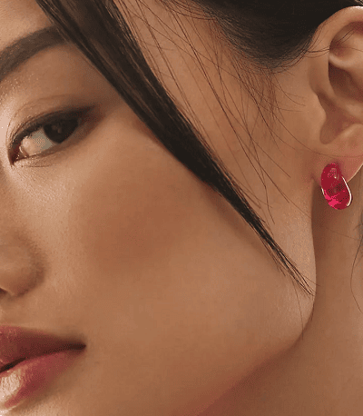 woman wears pink translucent huggie earrings