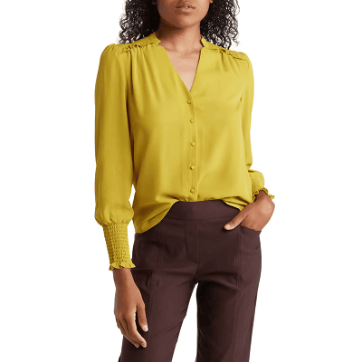 woman wears chartreuse blouse with smocked details at the shoulder and cuffs