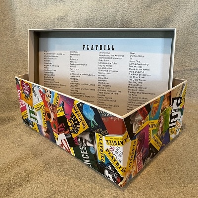 A storage box decorated with a Playbill collage and a list of musicals on the inside of the lid