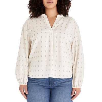 A woman wearing a print popover top and blue jeans