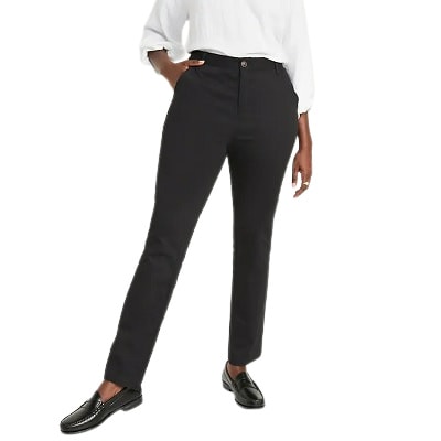 A woman wearing a white blouse, black pants, and black loafers
