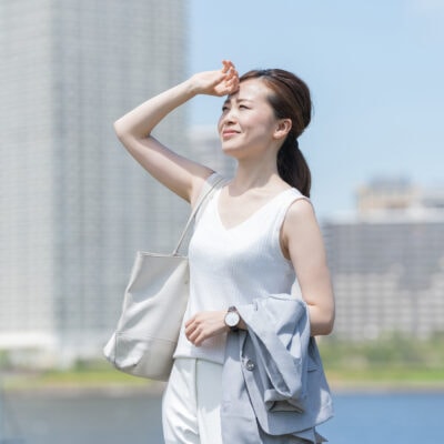 Asian businesswoman wipes sweat off her brow in summer heat