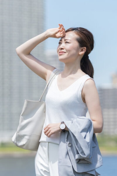 Asian businesswoman wipes sweat off her brow in summer heat