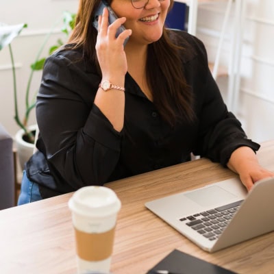 confident stylish plus-sized woman works at a desk and wonders where to get plus-size work clothes for her office