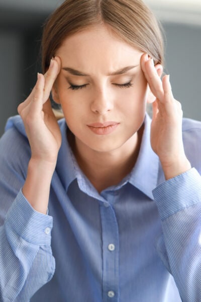 young professional woman is experiencing sensory overload at work and rubbing her temples