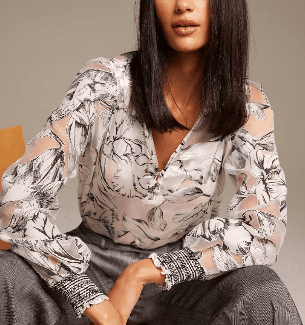 A woman wearing a white floral blouse