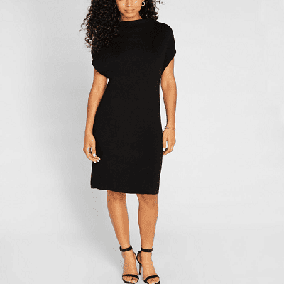 A woman wearing a black ribbed wool dress and a pair of black heels