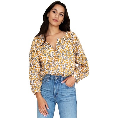 A woman wearing a yellow floral top and blue jeans